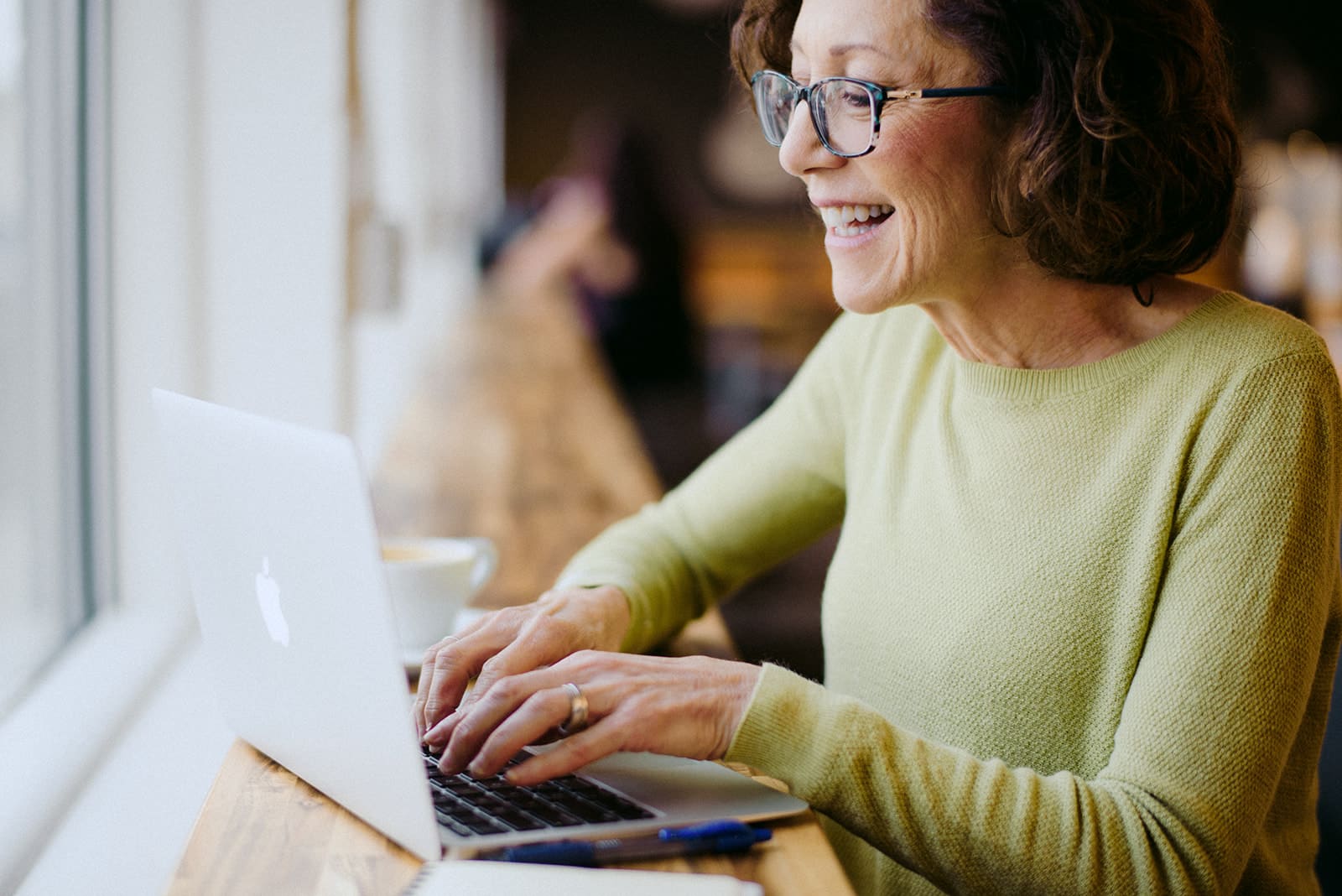 smiling woman looking at laptop in coffee shop