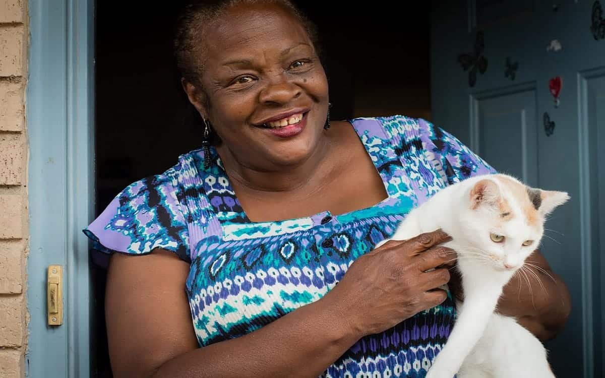 Woman smiling in opening of a front door with cat in her arms