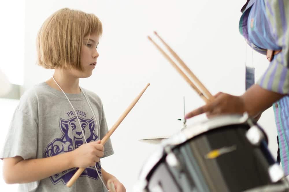 Teacher showing young girl how to play drums at Omaha Girls Rock