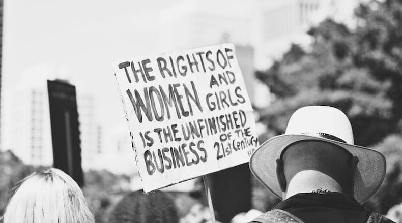 Black and white photograph showing protest and sign that says The Rights Of Women And Girls Is The Unfinished Business of the Twenty First Century